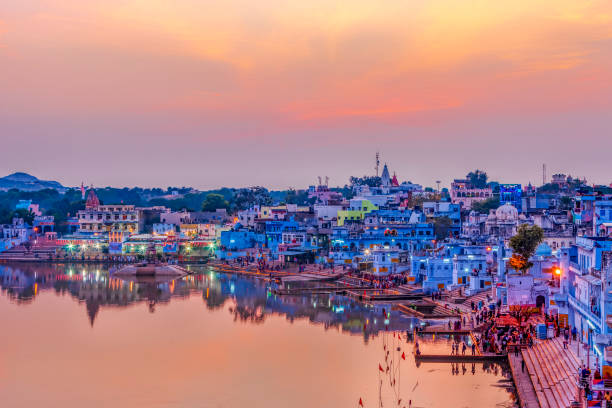 Pushkar Holy Lake at sunset. Hindu pilgrims bathing in sacred Lake Pushkar (Sarovar) on ghats. Countless people in colourful attire gather to take a dip in the Holy Lake and pray to deities.